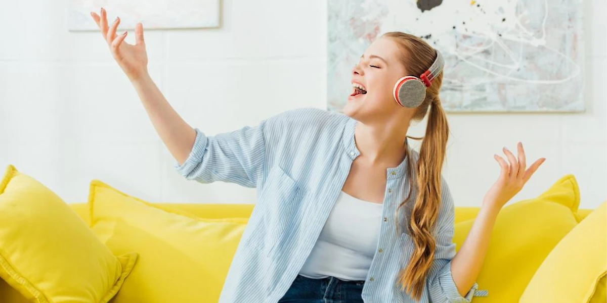 happy woman singing in an yellow sofa