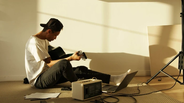 musician playing guitar in front a chrome os laptop