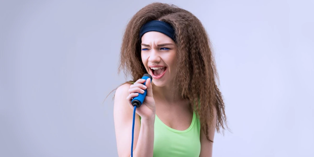 woman in fitness clothes singing on skipping rope on white