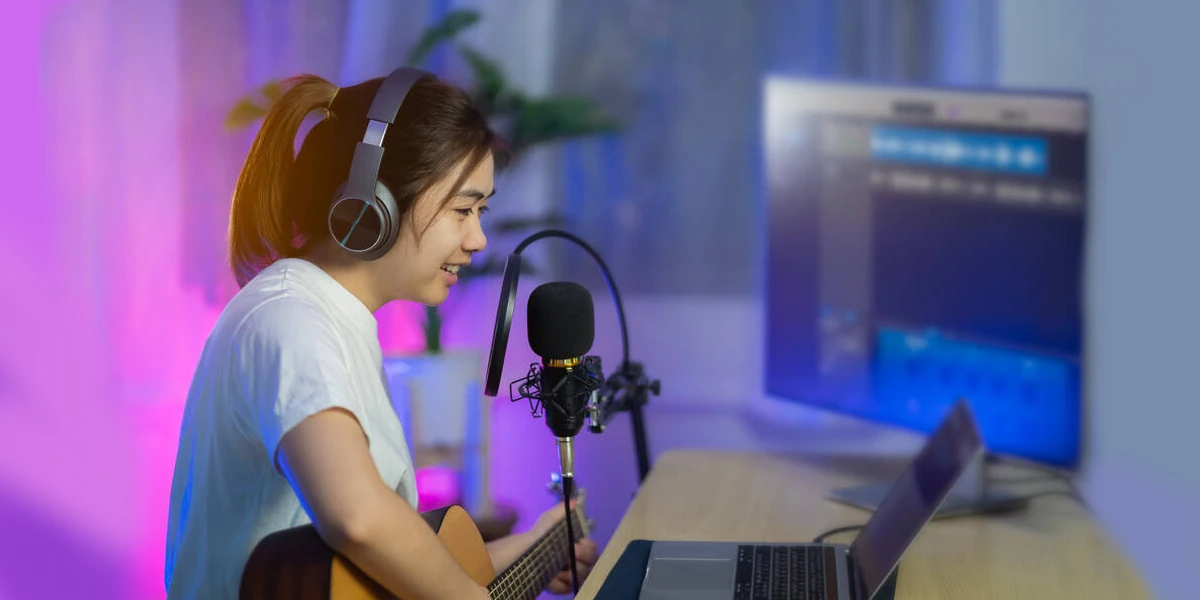 girl recording acoustic guitar in front of a computer